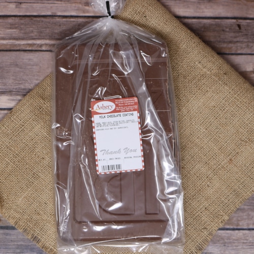 A clear plastic bag containing a slab of Milk Chocolate Coating sealed with a twist tie on rustic burlap with a wooden background.