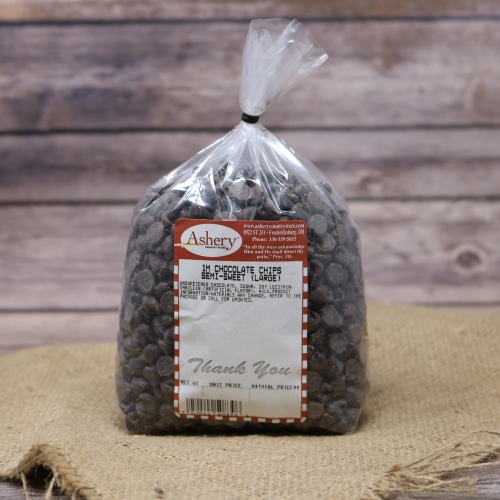 A clear plastic bag of Semi Sweet Chocolate Chips Large sealed with a twist tie on rustic burlap with a wooden background.