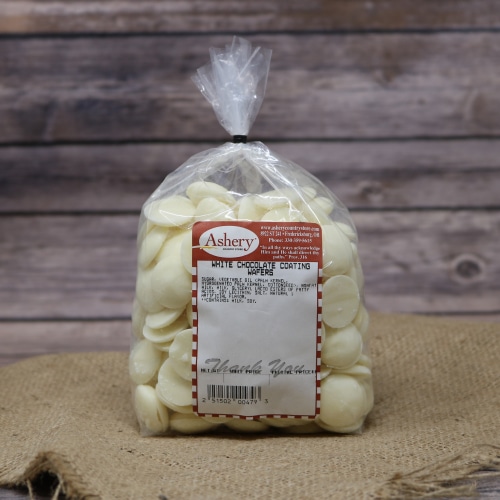 A clear plastic bag of White Chocolate Coating Wafers sealed with a black tie on rustic burlap with a wooden background.