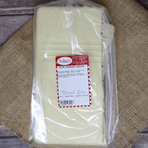 A clear plastic bag containing a slab of White Chocolate Coating sealed with a twist tie on rustic burlap with a wooden background.