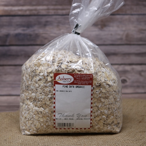A bag of Fine Oats Organic sealed with a black twist tie on rustic burlap with a wooden background.