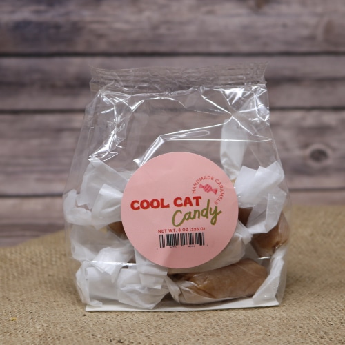 A clear 8 oz bag of individually wrapped Handmade Caramels on rustic burlap with a wooden background.