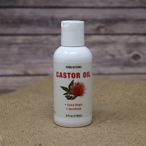 A white bottle of Herbal Blessings Castor oil 4oz on rustic burlap with a wooden background.