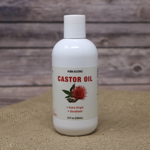 A white bottle of Herbal Blessings Castor oil 8oz on rustic burlap with a wooden background.
