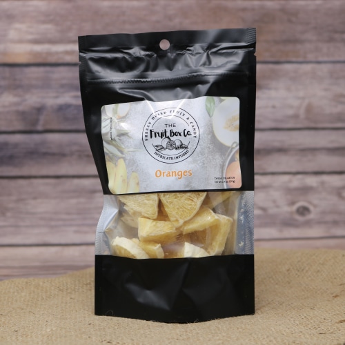 A black resealable bag with a clear window revealing Oranges Freeze Dried on a rustic burlap with a wooden background.