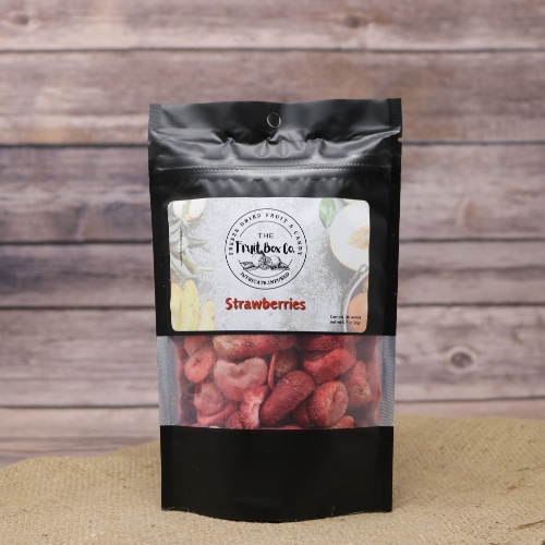 A black resealable bag with a clear window revealing Strawberries Freeze Dried on a rustic burlap with a wooden background.
