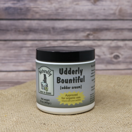 A round container containing Udderly Bountiful Cream on rustic burlap with a wooden background.
