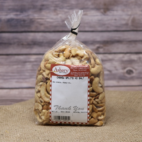A clear plastic bag of Cashew Splits No Salt sealed with a black twist tie on rustic burlap with a wooden background.