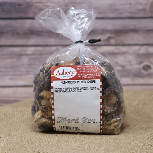 A clear bag of Mushrooms Mixed Chips, containing shiitake, oyster and button mushrooms, sealed with a black twist tie on rustic burlap with a wooden background.
