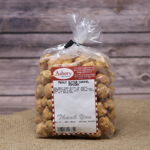 A clear bag of Peanut Butter Caramel Popcorn sealed with a twist tie on rustic burlap with a wooden background.