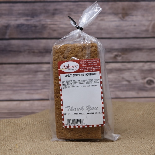 A small clear bag of Spelt Crackers Homemade on rustic burlap with a wooden background.