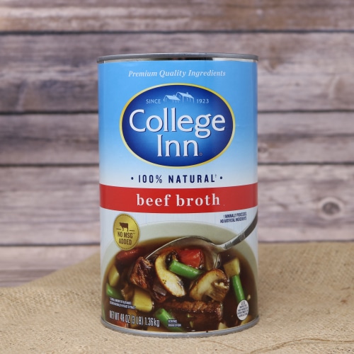 A tall tin can of 100% natural Beef Broth 48 oz on rustic burlap with a wooden background.