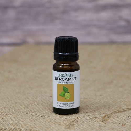 A small glass bottle of Bergamot Oil 1/3 fluid oz on rustic burlap with a wooden background.