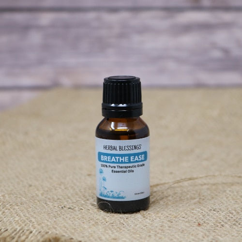 A small glass bottle with a blue label of Breathe Ease Oil on rustic burlap with a wooden background.