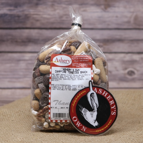 A clear bag sealed with a black twist tie of Campfire Toasties Snack Mix on rustic burlap with a wooden background.