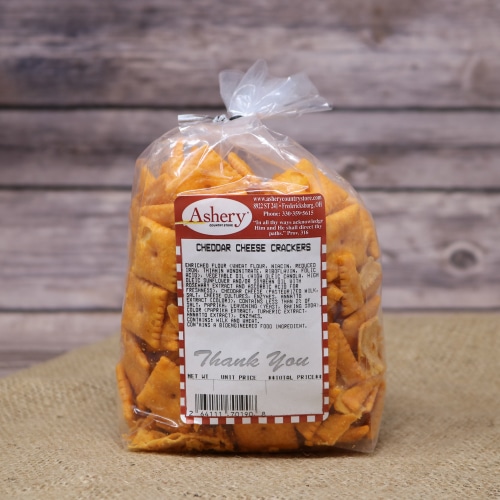 A clear plastic bag sealed with a black twist tie of Cheddar Cheese Crackers on rustic burlap with a wooden background.
