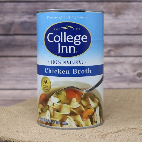 A tall tin can of 100% natural Chicken Broth 48 oz on rustic burlap with a wooden background.