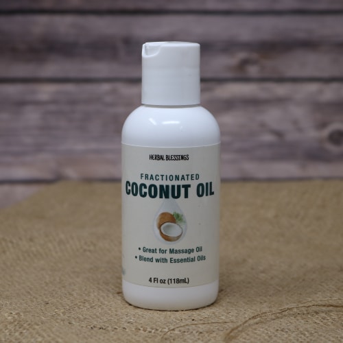 A small white bottle with green writing of Coconut Oil Fractionated on rustic burlap with a wooden background.