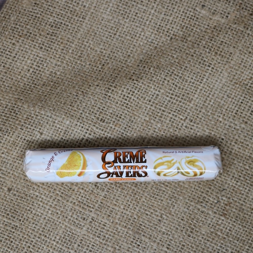 A small thin package containing 12 individually wrapped Creme Savers Orange on rustic burlap with a wooden background.