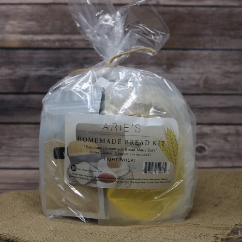 A bag tied with brown string containing a Homemade Wheat Bread Kit In Bag on rustic burlap with a wooden background.