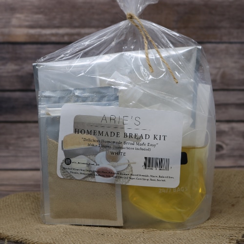 A bag tied with brown string containing a Homemade White Bread Kit In Bag on rustic burlap with a wooden background.