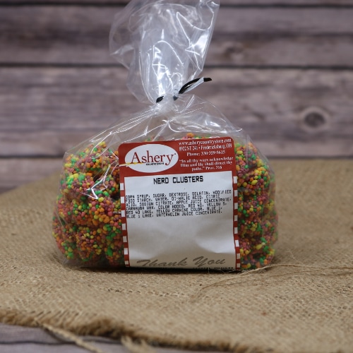 A clear plastic bag sealed with a black twist tie containing small, delicious Nerd Clusters on rustic burlap with a wooden background.