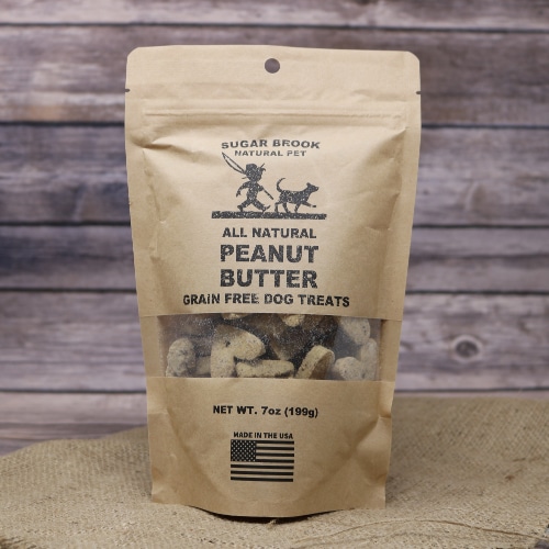 A brown bag of Peanut Butter Grain Free Dog Treats on rustic burlap with a wooden background.