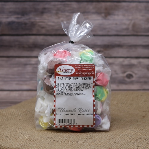 A clear plastic bag sealed with a black twist tie of Salt Water Taffy Assorted on rustic burlap with a wooden background.
