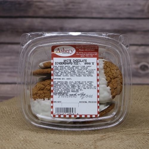 A clear container of White Chocolate Gingersnaps on rustic burlap with a wooden background.