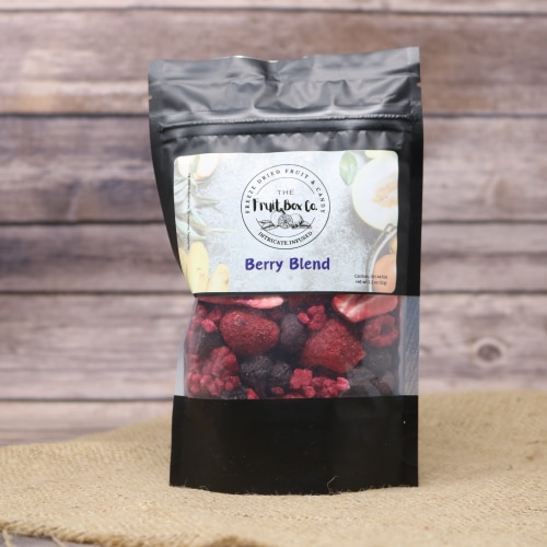 A black bag with a clear window revealing Freeze Dried Berry Blend on a rustic burlap with a wooden background.