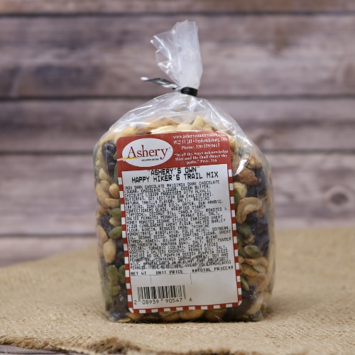 A small clear plastic bag sealed with a twist tie of Happy Hikers Trail Mix on rustic burlap with a wooden background.